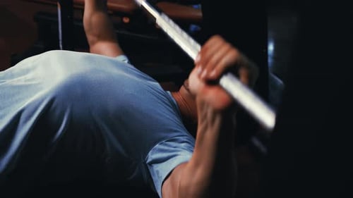 Muscular Adult Does Bench Press in Gym