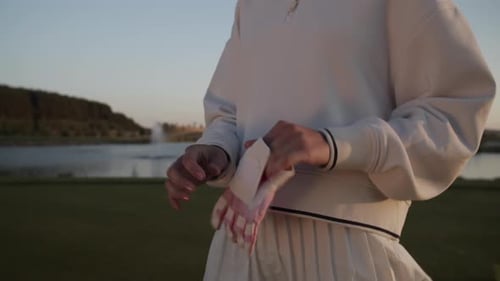 Woman Player Puts on Pink Sports Glove on Luxurious Golf Course