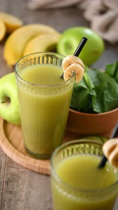 Hand Picking Up a Green Smoothie from the Table