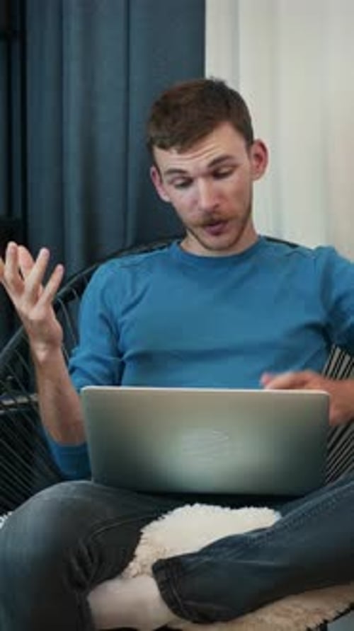 Man video conferencing on laptop in living room