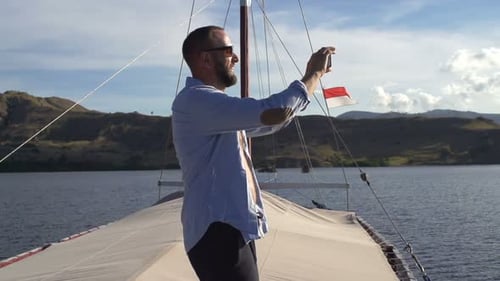 Man on Sailboat Taking Pictures with his Cellphone