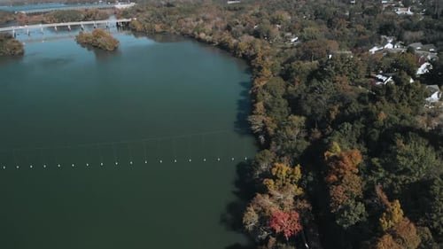 Aerial shot above beautiful river, water bride and forest trees in autumn