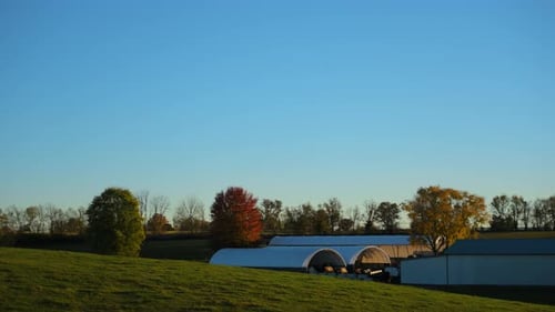 Wide View of Rural Farmland with Barns Fenced Fields and Open Countryside Under a Clear Blue Sky