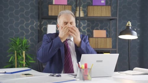 Senior Man Working at Desk Coughing and Blowing Nose