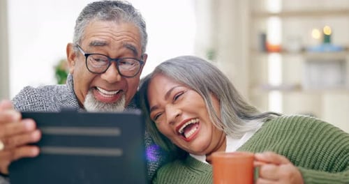 Senior Couple Laughing Together Looking at Tablet