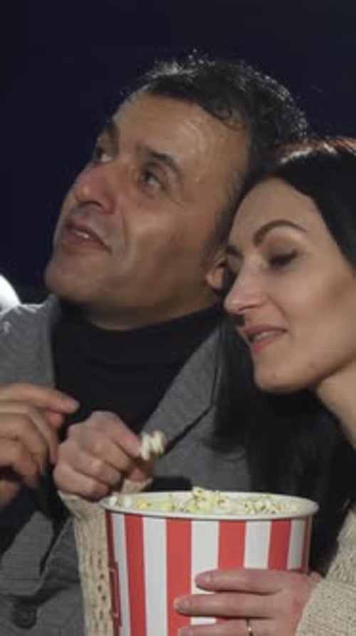Mature Couple Sharing a Joyful Movie Date at the Cinema with Popcorn