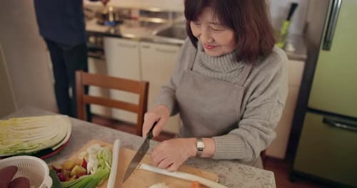 Senior woman, knife and vegetables in kitchen with cutting, smile and meal prep for wellness
