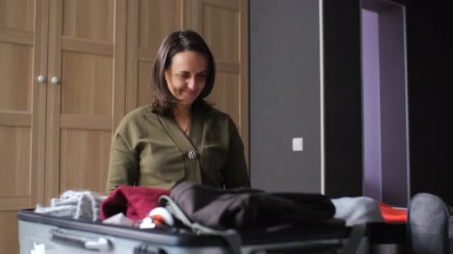 Woman Folding Clothes and Packing Suitcase