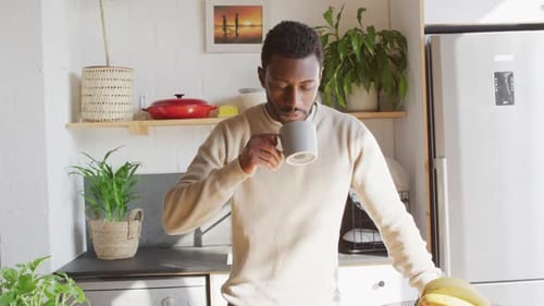 Young Man Drinking Coffee in Modern Kitchen