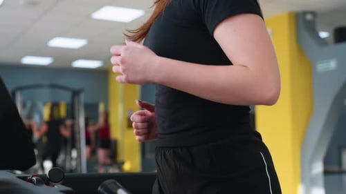 Close Up of Young Woman Running on Treadmill with Blurred Gym Background