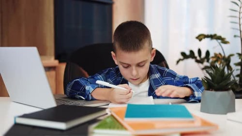 Busy School Boy Making Notes in Copybook During Online Classes at Home Interior