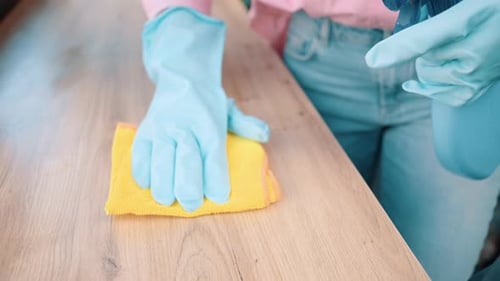 Close up shot of Housewife in blue rubber gloves washes, spraying windowsill at room
