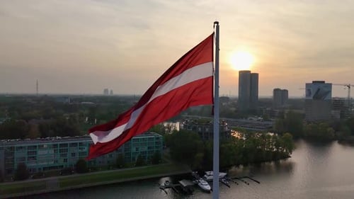 Aerial View of Latvian Flag Waving on Flagpole in Capital City Riga at Sunset Daugava River Slow