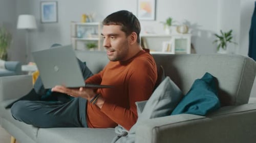 Man Relaxes on Couch Using Laptop Computer