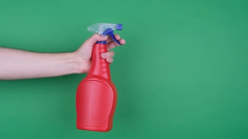Hand Holding a Red Spray Bottle on Green Screen