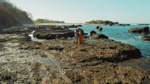 Couple exploring rocky tropical coastline with turquoise sea in Costa Rica