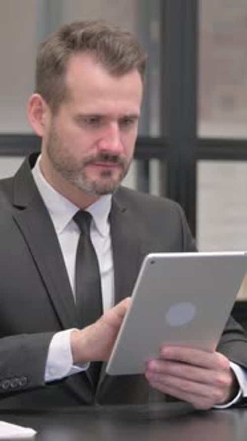 Upset Business Man Using a Tablet at Work