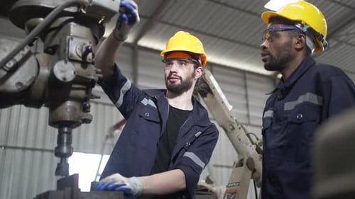 Des ouvriers travaillant dans un atelier d'usinage avec un bras robotisé de soudage.