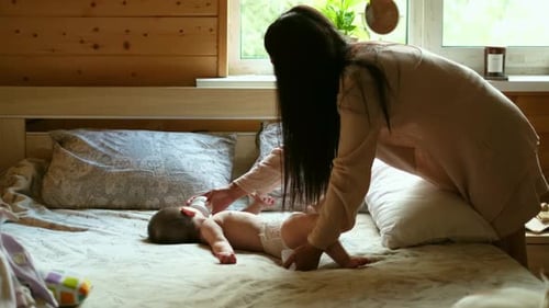 Woman Feeds Infant with Bottle on Bed