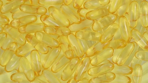Group of Yellow Gel Vitamin Capsules in Daylight