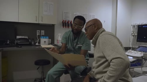 Male Doctor Discussing Medical Chart with Patient in Clinic Exam Room 10 Seconds or Greater