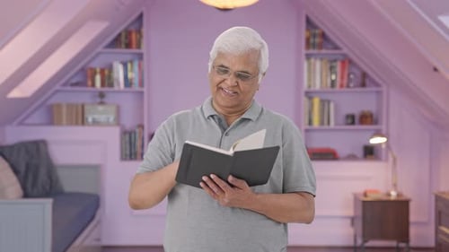 Senior Man Reads Book at Home and Smiles
