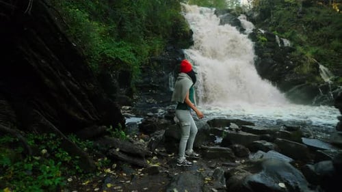 Young Adult Woman In Sportswear Walking Alone Near Small Waterfall In Forest In Weekend Trip