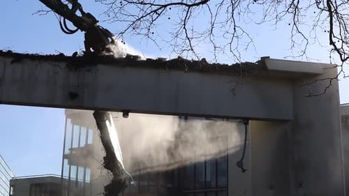Demolition crane spraying water when working on destruction zone.