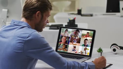 Caucasian male teacher using laptop on video call with school children