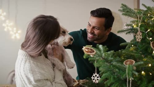 Couple Decorating Christmas Tree with Dog