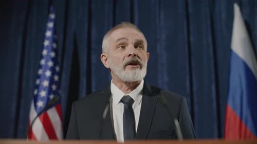 Mature Adult Giving Speech Near Flags