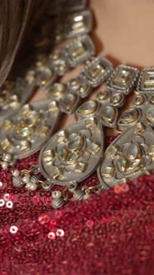Gros plan d'un collier ethnique orné de pierres précieuses sur un tissu à paillettes rouges