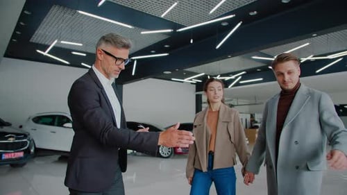 Salesman Talks to Customers Presenting New Cars in Dealership