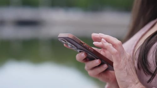 Close Up of Female Hands Writing a Message on a Smartphone in the Summer on the Street