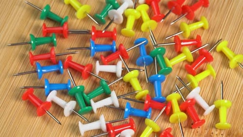 Colorful push pins rotating on the desk. Drawing pins for marking on the map of the Earth or city