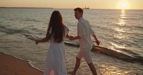 Young Loving Couple Enjoying Relaxing Sunset Walk on the Beach