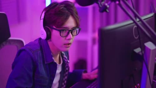 Young Adult Playing Computer Game with Purple Lighting