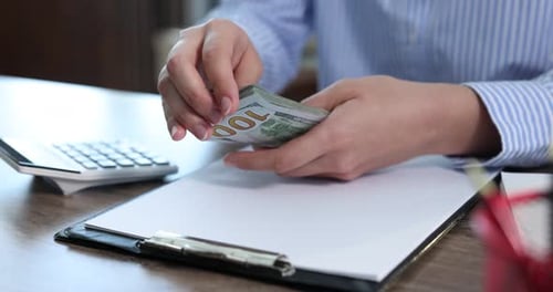 Counting Money at Desk with Calculator and Paper