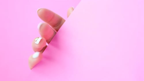 Female hand with white manicure on pink background, top view.