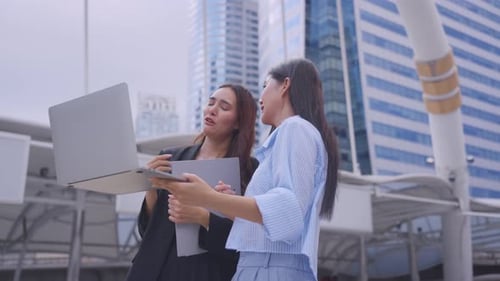 Asian two businesswoman walking with confidence outdoors in the city.