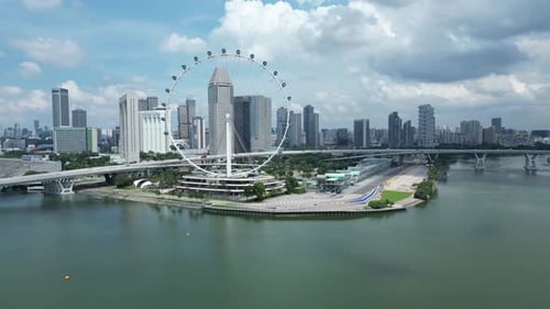 Drone wide shot of Singapore Flyer Eye, camera orbiting around Marina Bay F1 track with Singapore Ai
