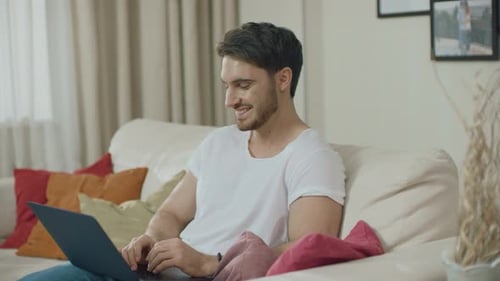 Man relaxes on couch using laptop computer