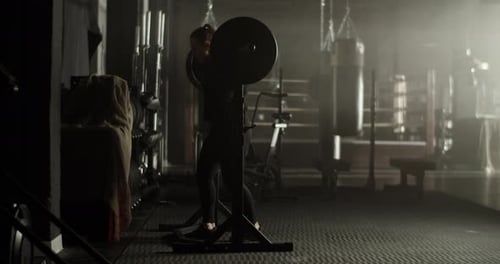 Strong Young Female Athlete Squatting with Barbell in Gym