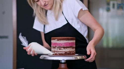 Woman Decorating Cake With Frosting in Kitchen