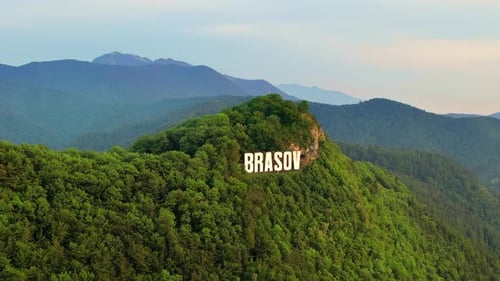 Brasov sign on the top of the hill near the city, green trees, Romania