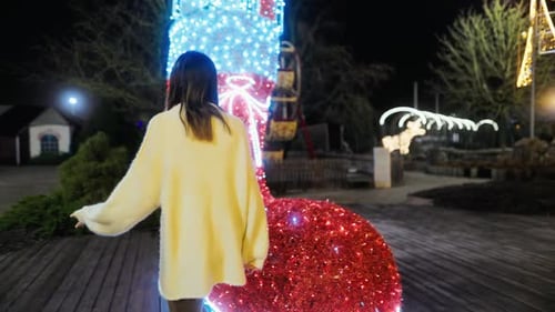 Festive Woman Poses Near Giant Christmas Stocking at Night
