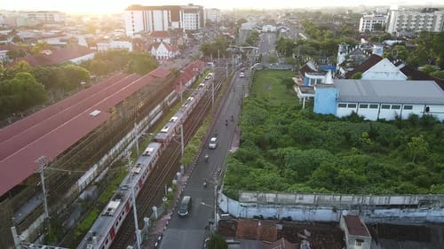 Aerial view of passenger train crossing rail bridge in near Tugu Station.
