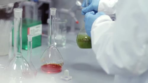Scientist working with chemical reaction in chemistry research lab in glass flask