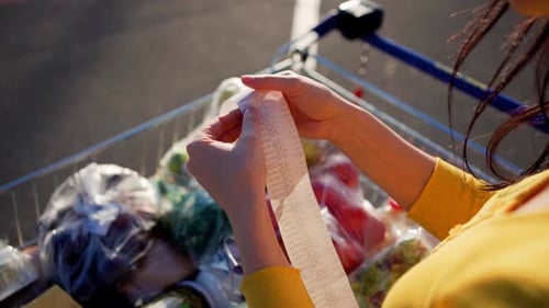 Top View Woman Checks Paper Check After Shopping for Groceries at Mall By Checking Dear Amount Bill