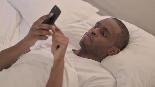 Man Lying in Bed Using Mobile Phone